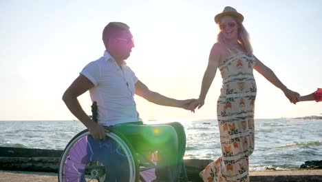 pregnancy,-summer-holidays,-disabled-man,-pregnant-girl-and-kid-with-balloons-walk-at-beach-in-backlight,-daddy