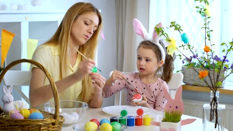 Happy-Easter!-Mother-and-her-little-daughter-wearing-funny-rabbit-ears-coloring-easter-eggs