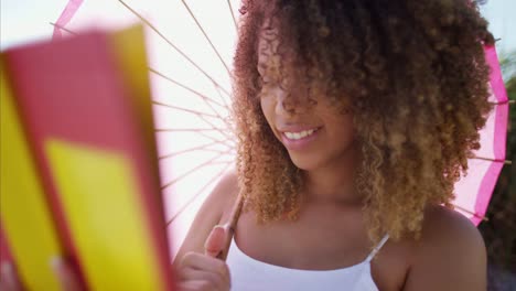 African-American-female-reading-under-parasol-on-beach