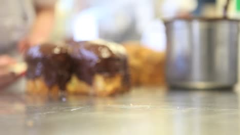 pastry-chef--hands-glazed-Easter-sweet-bread-cakes-with-chocolate,-closeup-on-the-worktop-in-confectionery