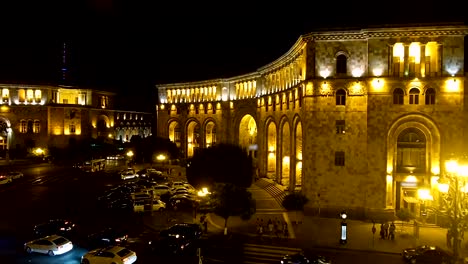 Coches-conduce-lentamente-a-través-de-la-Plaza-de-la-República-de-noche-en-Ereván,-luces-en-la-ciudad-de