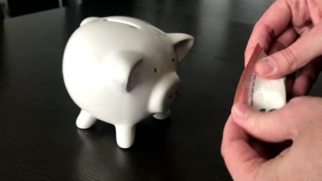 Frau,-eine-zehn-Euro-Banknote-in-ein-Sparschwein