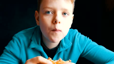 Mouth-of-a-teenager.-The-boy-with-an-appetite-eats-big-hamburger-in-a-fast-food-restaurant