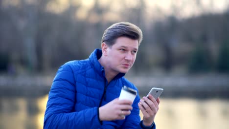 A-young-attractive-man-is-using-a-mobile-phone-at-sunset.