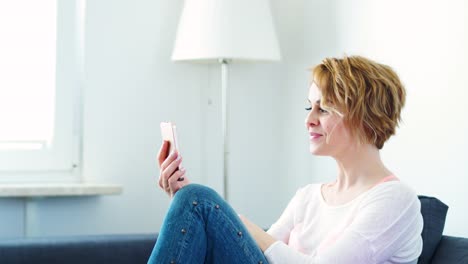 Frau-sitzt-auf-einem-grauen-Sofa-und-im-video-Chat