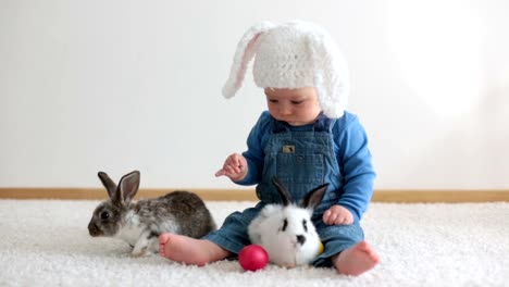 Little-toddler-child,-baby-boy,-playing-with-bunnies-and-easter-eggs-at-home,-colorful-hand-drawings-on-the-eggs.