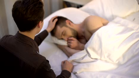 Young-man-stroking-sleeping-partner-head,-homosexual-couple,-tender-relations