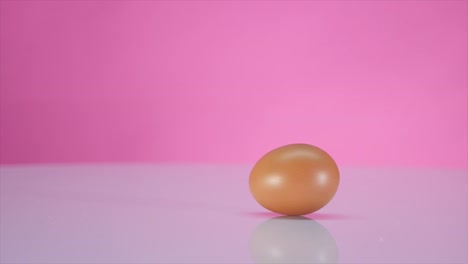 The-egg-spins-on-a-table-on-a-pink-background