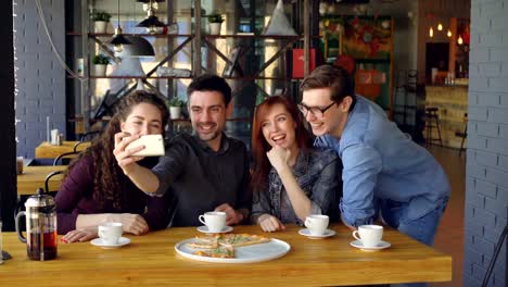 Emocionales-jóvenes-toman-selfie-con-smartphone-posando-y-riendo-en-el-café-moderno.-Concepto-moderno-de-la-tecnología,-diversión,-Milenio-y-la-amistad.