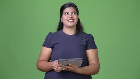 Young-overweight-beautiful-Indian-businesswoman-against-green-background