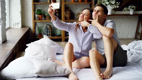 Bonita-chica-está-tomando-selfie-con-su-guapo-novio-caucásico-con-smartphone-posando-y-besos.-Relación-romántica-y-concepto-de-redes-sociales.