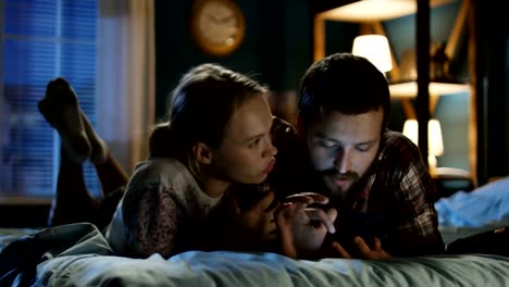 Young-couple-surfing-smartphone-on-bed