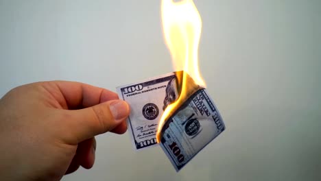 Mano-que-sostiene-un-billete-de-cien-dólares-ardiente