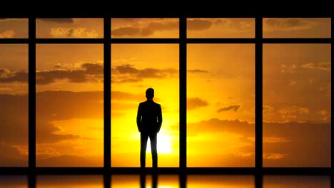 The-man-standing-near-panoramic-windows-on-the-sunset-background.-time-lapse