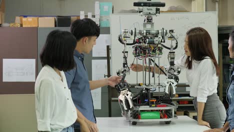 Electrónica-de-joven-ingeniero-equipo-colaborando-en-la-construcción-del-robot-en-el-taller.-Ingeniero-de-equipo-pone-en-marcha-proyecto-de-robot-juntos.-Personas-con-el-concepto-de-tecnología-o-innovación.