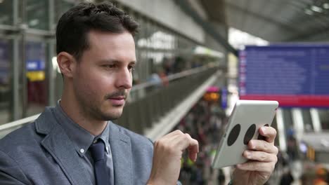 Guapo-joven-empresario-escribiendo-textos-sobre-tableta-digital-en-el-espacio-público