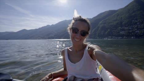 Joven-tomando-retratos-selfie-en-canoa-roja-montaña-lago-una-mujer-disfruta-vacaciones-de-verano-tener-diversión-en-actividades-al-aire-libre---lenta