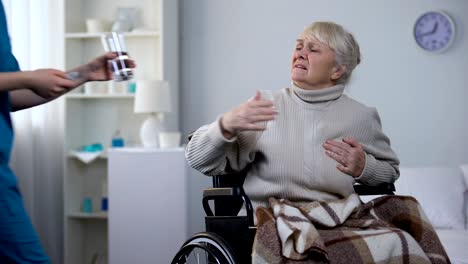 Old-lady-in-wheelchair-feeling-heart-pain,-asking-nurse-for-pills,-hospital-care