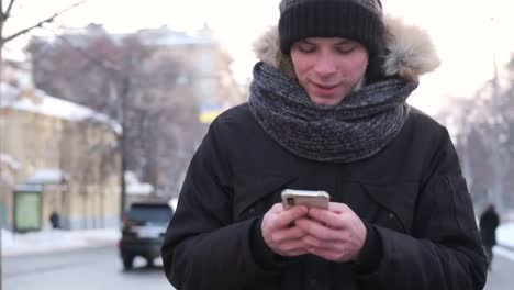 Man-walking-and-using-mobile-phone-on-a-cold-winter-day