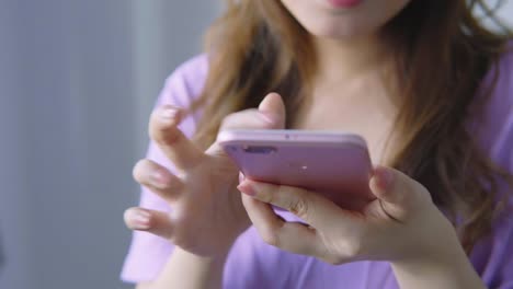 Mujer-asiática-usando-teléfono-celular-en-la-sala-de-estar