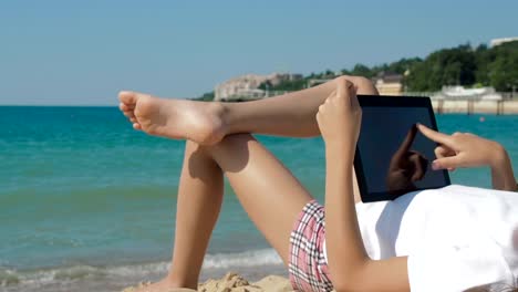 Child-using-tablet-on-beach.-Child-lying-on-beach.