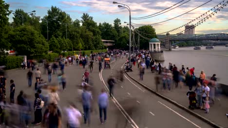 Menschenmassen-spazieren-entlang-der-Uferpromenade-eines-Stadtflusses,-Zeitraffer