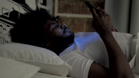 African-Man-Using-Smartphone-in-Bed-at-Night