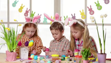 Happy-children-wearing-bunny-ears-painting-eggs-on-Easter-day.-Little-girls-preparing-for-the-Easter.