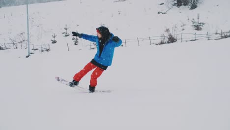 Männlicher-Snowboarder-fährt-auf-einem-Brett-im-Schnee-von-der-Skipiste