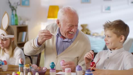 Grandfather-Playing-with-Grandson-while-Painting-Eggs