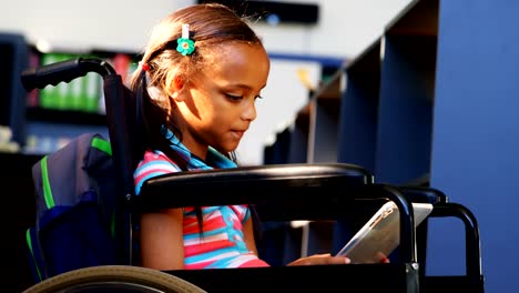 Side-view-of-disabled-African-American-schoolgirl-reading-a-book-in-library-at-school-4k