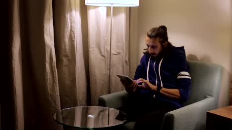 Handsome,-young-man-with-tablet-computer-sitting-on-chair-at-home