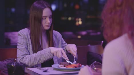 Two-cute-girlfriends-have-dinner-in-a-modern-restaurant-together.