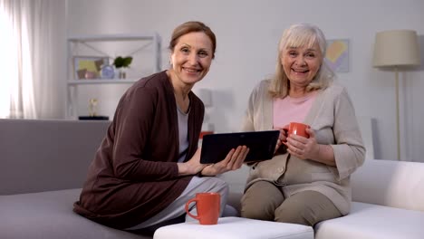 Mujeres-mayores-sonriendo,-viendo-espectáculo-de-entretenimiento-en-la-tableta,-internet-rápido