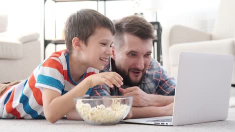 Vater-und-Sohn-lachen,-während-sie-den-Film-auf-dem-Laptop-sehen