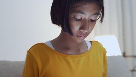 Little-asian-girl-using-tablet-on-sofa-in-home-at-night