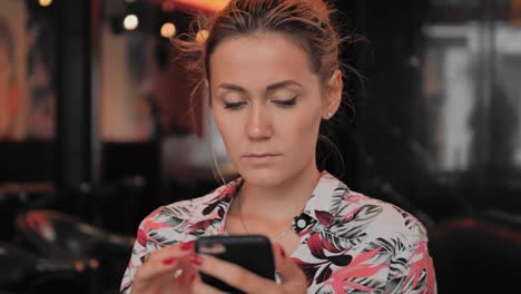 Caucasian-young-female-uses-smartphone-while-sitting-in-a-restaurant.-Slow-Motion