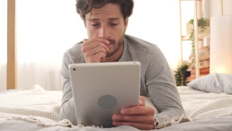 Confused-man-using-digital-tablet-in-bed