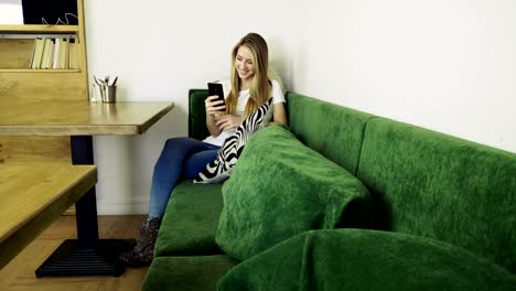 Atractiva-joven-mujer-feliz-usando-el-teléfono-móvil-durante-el-descanso-en-un-café.-4K