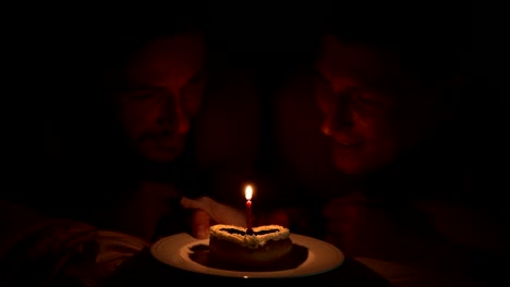 Pareja-gay-disfrutar-de-su-pastel-de-cumpleaños-juntos-en-la-cama.-Haciendo-un-deseo.