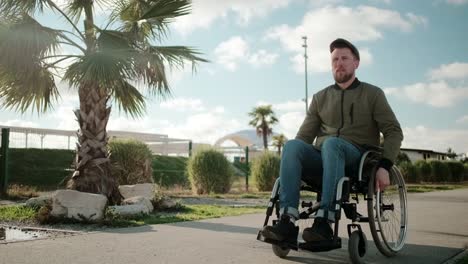 Man-with-paralysis-of-legs-muscles-is-sitting-in-invalid-carriage-and-riding