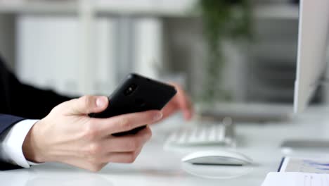 Hands-of-Businessman-Typing-on-Keyboard-and-Using-Smartphone