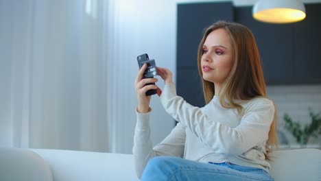 Set-up-the-app-to-pay-for-purchases-with-your-smartphone.-Young-beautiful-woman-shopping-from-the-comfort-of-home-sitting-on-the-couch