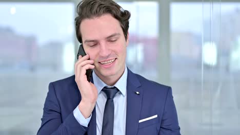 Portrait-of-Cheerful-Young-Businessman-Talking-on-Smartphone