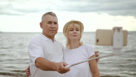 Mature-happy-couple-taking-picture-on-weekend-with-sea-behind