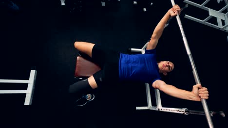 La-vista-superior-de-un-hombre-con-una-pierna-biónica-está-levantando-un-bar-en-el-gimnasio