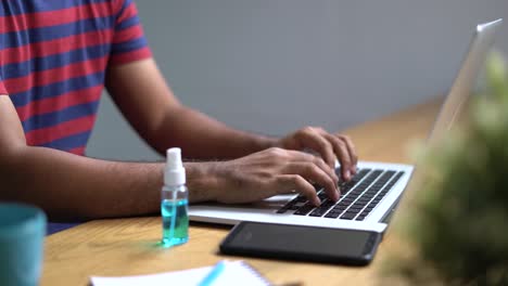 Soziale-Distanz-und-Arbeit-bilden-Hauskonzept,-nah-bei-der-Nähe-Geschäftsmann-asiatische-Mann-reinigung-seine-Hände-mit-Alkohol,-bevor-sie-Laptop-im-Wohnzimmer-während-der-Absperrung-Situation.