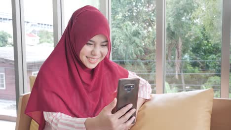 Happy-muslim-woman-using-smartphone-for-video-call-in-home.