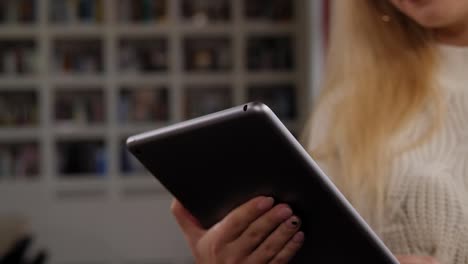 Close-up-of-a-young-woman-holding-a-tablet-in-the-library.