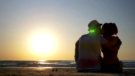 Pareja-amorosa-joven-sentado-en-una-playa-y-besos